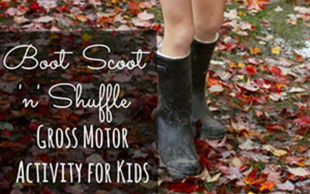 A child in boots shuffles leaves with her feet.