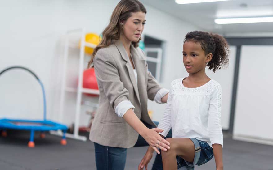 A physical therapist working with a young girl.