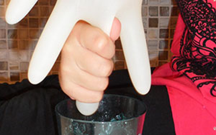 A child "milking" a rubber glove into a glass.